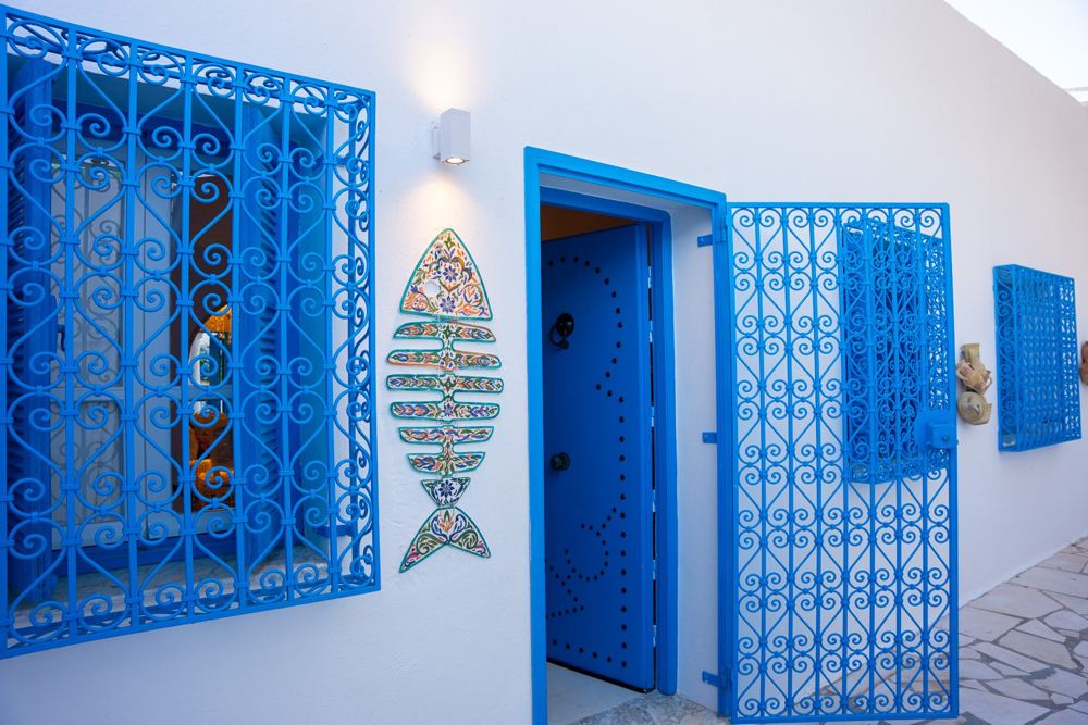 Façade blanche, porte et grilles en fer forgé bleu